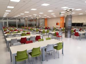 uma cafetaria com mesas brancas e cadeiras verdes em Albergue Residencia Larraona em Pamplona