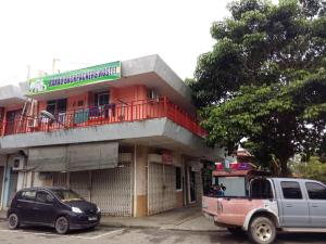 a building with a truck parked in front of it at Ranau Backpackers Hostel in Ranau