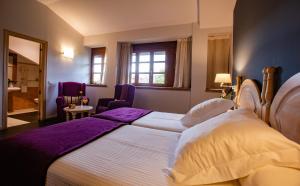 オビエドにあるHotel Palacio De La Viñonaのベッドルーム1室(紫のシーツが敷かれた大型ベッド1台付)