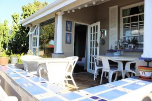a patio with white chairs and tables on a house at Baylight Accomodation in Mossel Bay