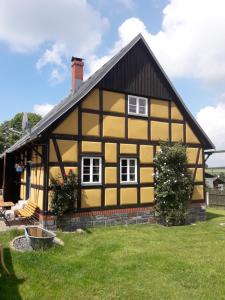 ein gelbes und schwarzes Haus mit einem Rasenplatz in der Unterkunft Ferienhaus Brotenfeld in Brotenfeld