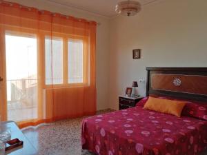 1 dormitorio con cama roja y ventana en Alojamiento Rural, en Tobarra