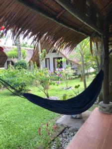 a hammock hanging from a roof in a garden at Villa Paradise in Bukit Lawang