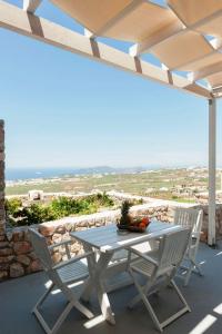 un tavolo e sedie su un patio con vista sull'oceano di Zatrikion Santorini Villas a Pyrgos
