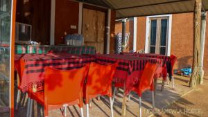 a table with orange chairs and a red and black table cloth at Pidurangala Hostel in Sigiriya