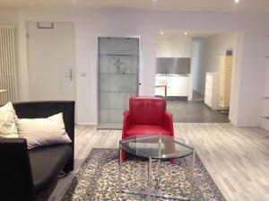 a living room with a red chair and a glass table at Stadtmitte Ferienwohnung Waldshut in Waldshut-Tiengen