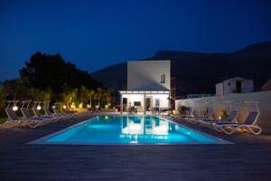 a swimming pool with chairs and a building at night at L' Arcobaleno B&B in Castelluzzo
