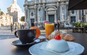 a table with a cup of coffee and a plate of food at Duomo Luxury Suite Catania in Catania