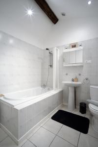 uma casa de banho branca com uma banheira e um lavatório em Les Gîtes de La Treille em Montagrier
