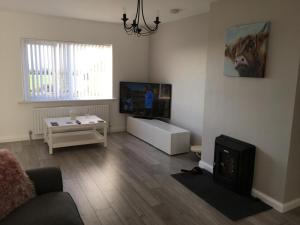 een woonkamer met een bank en een tv bij Byrestown Cottage in Kells