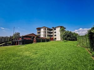 un grand jardin verdoyant avec un bâtiment en arrière-plan dans l'établissement Peponi Living Spaces, à Kigali
