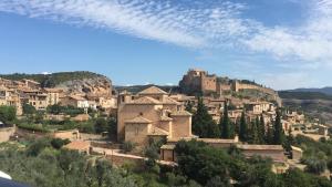 a village on a hill with a castle in the background at Apartamentos Residencial Fornocal in Alquézar