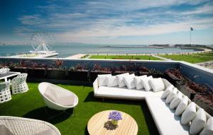 a balcony with a white couch and a table and chairs at Sheraton Baku Intourist in Baku