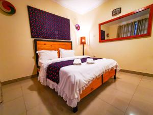 a bedroom with a large bed and a mirror at Peponi Living Spaces in Kigali