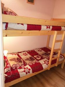 ラ・ジュー・デュ・ルーにあるLes Terrasses du Dévoluy, La Joue du Loupのベッドルーム1室(二段ベッド2台、赤と白の毛布付)