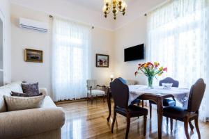 ein Wohnzimmer mit einem Tisch, Stühlen und einem Sofa in der Unterkunft Neoclassical apartment with 3 bedrooms in Piraeus in Piräus