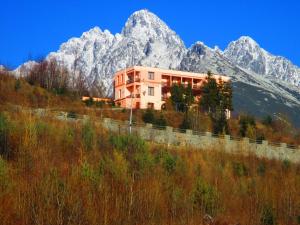 a building on a hill with mountains in the background at Penzion Partizan in Starý Smokovec