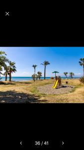einen Spielplatz am Strand mit Palmen und dem Meer in der Unterkunft Duplex La Cala in La Cala del Moral