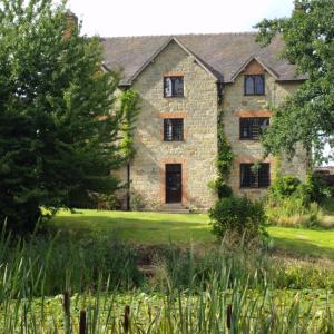 uma velha casa de pedra no meio de um campo em Abbey Farm Bed And Breakfast em Atherstone