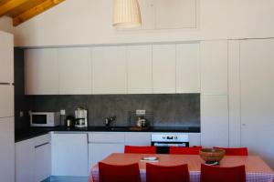a kitchen with a red table and red chairs at Casa do Sobreiro-Quinta do Briando in Portalegre