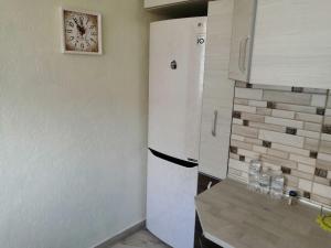Il comprend une cuisine équipée d'un réfrigérateur blanc et d'une horloge murale. dans l'établissement У Ксені, à Morshin