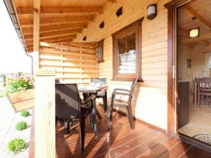 a wooden cabin with a table and chairs on a porch at Domki Marlin in Rewal