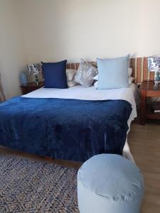 1 dormitorio con 1 cama con manta azul y taburete en Lady Loch Country House, en Wellington