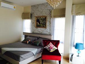 1 dormitorio con 1 cama y 1 silla roja en Peters Villa en Ban Nakhon Chum