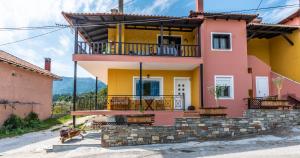 a pink and yellow house with a balcony at Demmy's Apartment in Potamiá