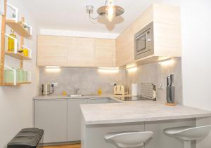 a kitchen with white cabinets and a counter with stools at Whitsun Cottage - A cosy one bedroom Victorian cottage sleeping up to 3 guests in Gosport