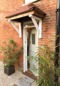 una casa de ladrillo con una puerta blanca con toldo en Whitsun Cottage - A cosy one bedroom Victorian cottage sleeping up to 3 guests en Gosport