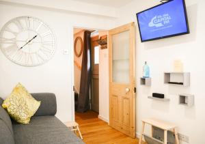 a living room with a couch and a clock on the wall at Whitsun Cottage - A cosy one bedroom Victorian cottage sleeping up to 3 guests in Gosport