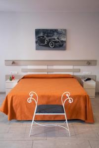 um quarto com uma cama com um cobertor laranja e uma cadeira em Apartamentos Comfort Calella em Calella