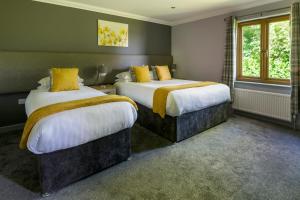 a bedroom with two beds with yellow pillows at Trethorne Hotel & Golf Club in Launceston