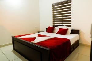 a bedroom with a bed with red and white pillows at Green Garden Lotus Villa in Kaniyāmbetta +22 photos