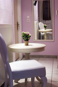 una mesa y una silla con un jarrón de flores. en Filyra Pension, en Nauplia