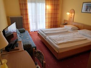 a hotel room with two beds and a flat screen tv at Vital & Wellnesshotel Schuerger in Thurmansbang