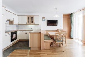 a kitchen with white cabinets and a table and chairs at Apartments Petlin in Ortisei +38 photos