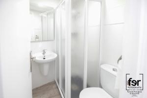 een witte badkamer met een toilet en een wastafel bij Pension Ramonetero in Águilas