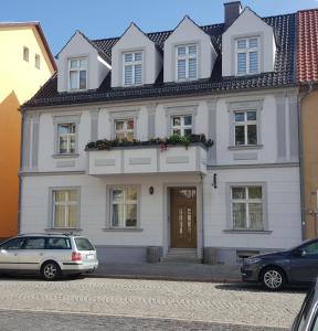 a white house with two cars parked in front of it at Fewo Am Marktplatz I in Eisenhüttenstadt