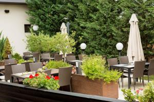 un patio con mesas, sillas y una sombrilla blanca en Hotel Galaxy, en Timisoara