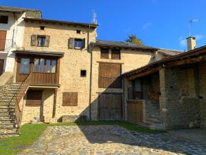 um antigo edifício de pedra com portas de madeira e um alpendre em Casa rústica actualizada en Oseja em Osséja
