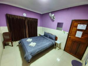 - une chambre avec un lit et un mur violet dans l'établissement Route 76 Guest House, à Saen Monourom