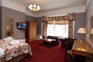 a hotel room with a bed, desk, chair and a lamp at Farington Lodge Hotel in Preston