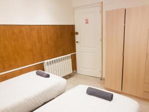 Habitación con 2 camas, armario y puerta. en Waves Guesthouse, en San Sebastián