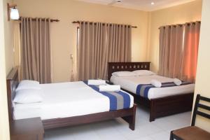 two beds in a hotel room with curtains at PJ Hotels Jaffna in Jaffna