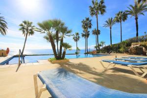 un resort con piscina, palme e oceano di Estepona Port Apartment LUNA a Estepona