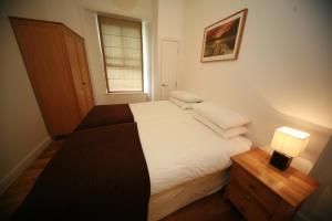 a small bedroom with a bed and a lamp at Chaucer Apartment in Keswick