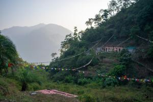 a string of flags on a hill with a house at TRIBE AQUA a nature retreat above Neer waterfall in Rishīkesh