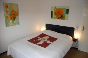 - une chambre avec un lit blanc orné de fleurs dans l'établissement Unter den Quellen, à Schwalefeld
